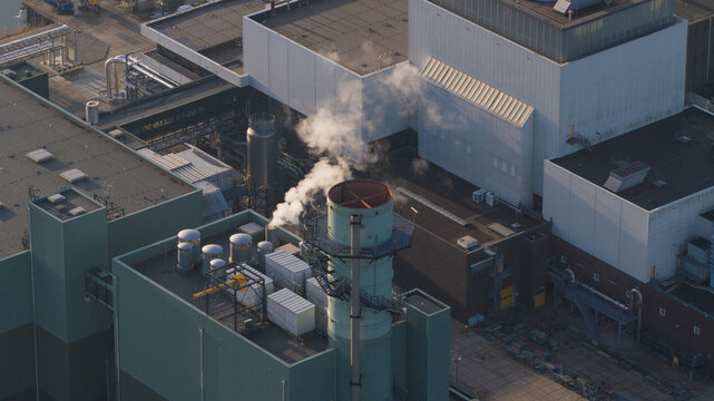 Aerial view of Vattenfall Elektriciteitscentrale Diemen with smoke rising from a chimney and industrial rooftops in Diemen, Noord-Holland, Netherlands.