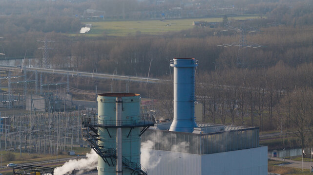 Aerial view of the Vattenfall Elektriciteitscentrale Diemen power plant with industrial chimneys emitting steam near an electrical substation in Diemen, Noord-Holland, Netherlands.