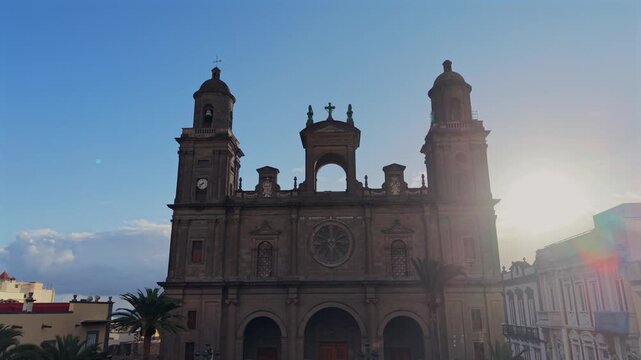 Backlit silhouette of Las Palmas Cathedral in Santa Ana Square revealing the facade against a clear blue sky at sunset