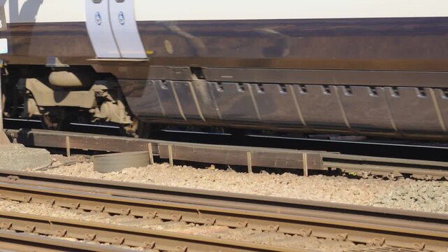 Commuter Passenger Train Passing By on Tracks in Slow Motion in UK. Public transportation, daily commute, urban travel, and fast-paced city life.