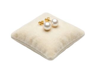 Elegant round white pearl stud earrings with gold posts resting on a soft cream velvet jewelry...