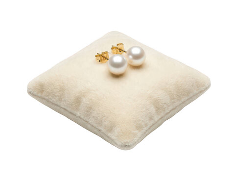 Elegant round white pearl stud earrings with gold posts resting on a soft cream velvet jewelry cushion for bridal gift presentation isolated transparent background image