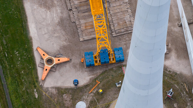 Aerial view of Westermeerdijk wind turbine construction site with a yellow crane, blue counterweights, and tower base Espel, Flevoland, Netherlands.
