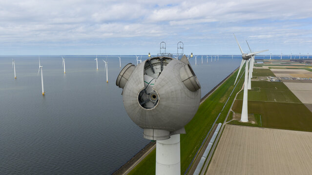 Aerial view of a wind turbine nacelle showing internal components with offshore and onshore wind farms along the coast in Espel, Flevoland, Netherlands.