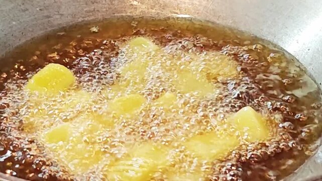 Sizzling golden brown potatoes cooking in deep fryer pan.&nbsp;