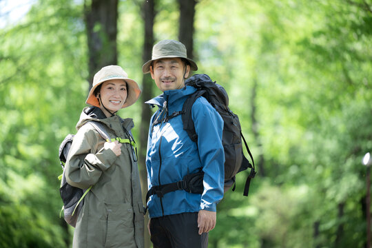 新緑のトレッキングや登山で笑顔のアウトドアやレジャーを楽しいミドルの夫婦のカメラ目線　右コピースペースあり