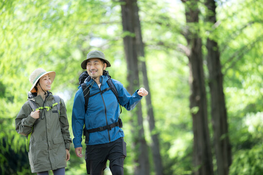 新緑の春の森の中を歩く夫婦のアウトドア、登山やトレッキングなどの運動イメージ上半身の笑顔