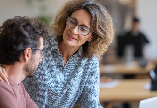 Mature female mentor guiding male mentee in office