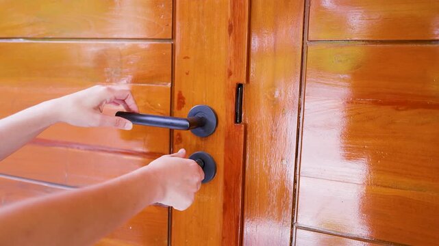 Close Up of Hands Unlocking and Opening a Wooden Door