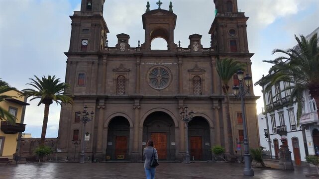 Woman exploring the historic Las Palmas Cathedral on a rainy day in Santa Ana Square, Gran Canaria, Spain