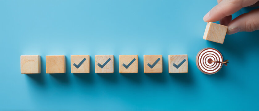hand pushing wooden blocks with a checkmark icon towards a goal target on a blue background.