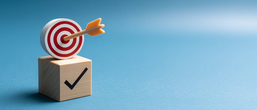 hand pushing wooden blocks with a checkmark icon towards a goal target on a blue background.