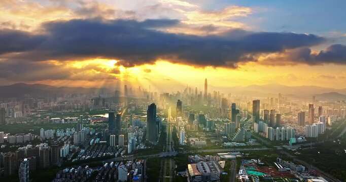 Aerial view of a dense modern skyline with skyscrapers under golden sunlight and sunbeams, Shenzhen, China