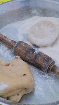 Unhygienic food preparation with flies sitting on wheat dough and rolling pin