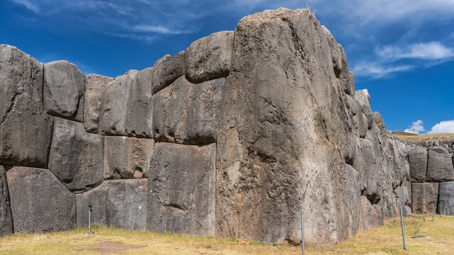 Ruins of the famous ancient Inca fortress Sacsayhuaman. The battlements are made of huge boulders, smoothly hewn and closely fitted.  Ashlar polygonal masonry. Blue sky, clouds. Peru. Cusco.