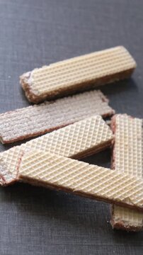 Crispy chocolate cream filled wafer biscuits on a dark textured surface