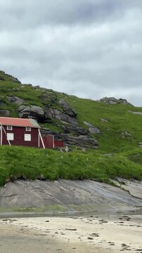 Lone red rorbu cabin by the shore near Bunes beach, Lofoten Islands, Norway