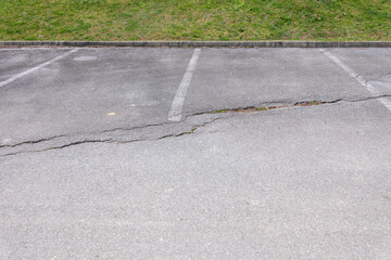 Obraz premium Damaged asphalt in a parking lot with cracks and deteriorated surface, infrastructure and maintenance problem in urban environment.
