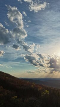 A vertically framed aerial hyperlapse ideal for mobile, social media, and reel formats. Dark roiling storm clouds dominate the upper half of the frame as dramatic golden light breaks through 