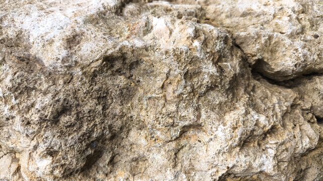 Old stone wall texture in extreme close up view showing rough rock surface detail, natural grunge pattern background, aged material backdrop perfect for design and construction concept