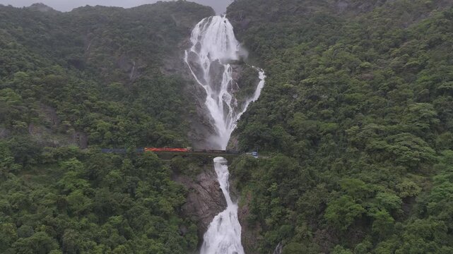 Aerial Slow motion View of Dudhsagar Waterfall with Train Crossing Bridge in Goa India