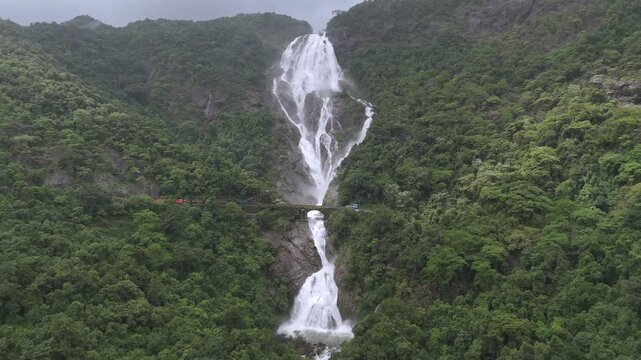 Aerial Slow motion View of Dudhsagar Waterfall with Train Crossing Bridge in Goa India