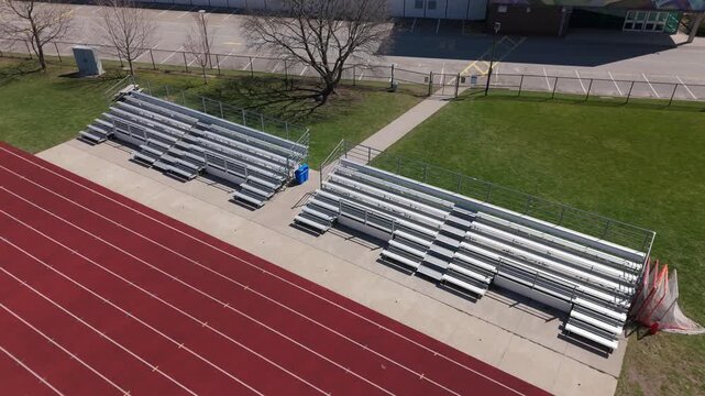 RIsing drone shot of empty bleachers with running track in foreground