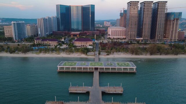 Aerial view of high-rise development at Otres Beach in Sihanoukville Province, Cambodia, with a long pier, beachfront towers, and coastal urban expansion along the sea.