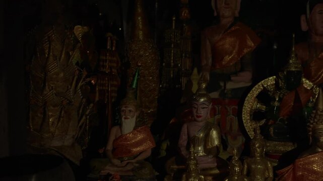 Smooth pass by of religious idols and figures in Phaya In Cave in Laos under dim lighting.