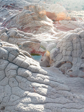 Aerial view of White Pocket featuring unique brain rock formations and small water pools with a person standing below in Coconino County, Arizona, United States.