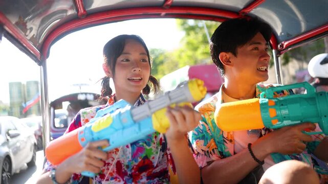 Asian Couple Celebrating Songkran Festival with Water Guns in a Tuk Tuk