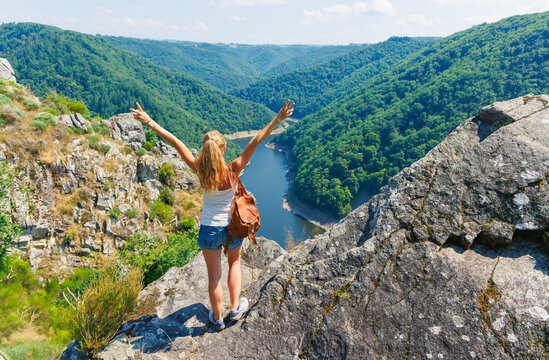 Woman hiker celebrating at Belvedere de Gratte-Bruyere overlooking Dordogne River Gorges, Correze, France. Travel lifestyle, freedom and nature exploration concept in Limousin region.