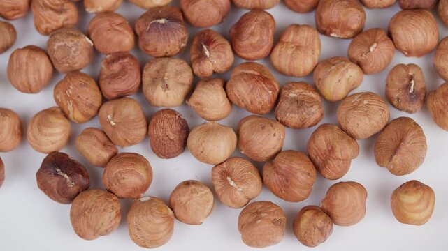 Roasted hazelnuts detail shot. Macro view of toasted hazelnail nuts on white. Detailed macro image capturing roasted hazelnut kernels with natural skins and crunchy surface