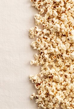 Top view of popcorn border on beige textured background with copy space, minimal snack food composition