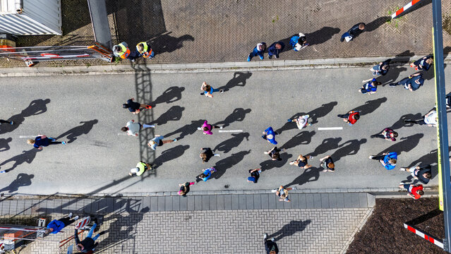 Aerial drone view of people running half marathon race in city, shadows of runners on road racing sport competition, top-down view of athletes and spectators, Venlo, the Netherlands
