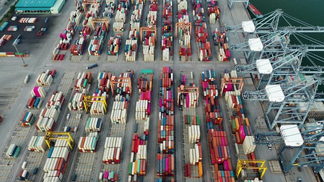 Aerial Top view of a large cargo ship loading and unloading containers at a deep-sea port. This aerial scene highlights global logistics, international trade, and maritime transportation hubs.