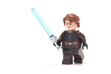 Naklejka premium Lego minifigure of Anakin from Star Wars with blue lightning sword isolated on white. Editorial illustrative image of popular plastic constructor.