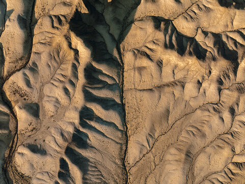 Aerial view of eroded badlands with deep ridges and shadows in the desert terrain near Hanksville, Utah, United States.