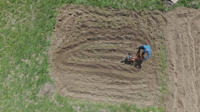 man using rotary cultivator on small field