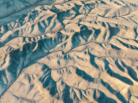 Aerial view of the intricate badlands and eroded desert ridges under soft light in Hanksville, Utah, United States.