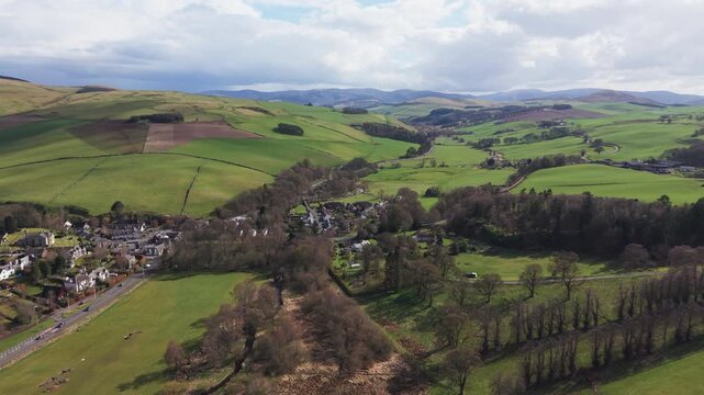 Traditional Scottish village of Eddleston surrounded by green farmland and rolling hills near Peebles. Scenic rural landscape featuring country houses and agricultural fields in Scotland.