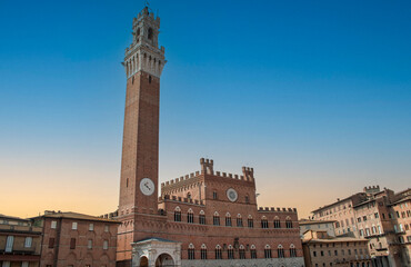 Obraz premium the sun sets over the Torre del Mangia located in Piazza del Campo in Siena, Italy.