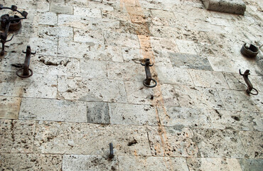 Obraz premium ancient wrought iron rings set in a stone wall.