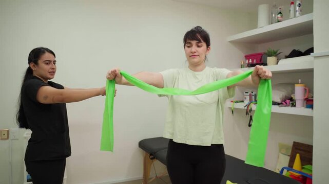 Physiotherapist guiding patient with resistance band exercises for shoulder rehabilitation, promoting mobility and strength recovery in a modern clinic environment