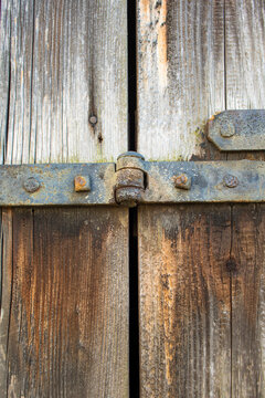an old, rusty iron hinge on a weather-weathered wooden door