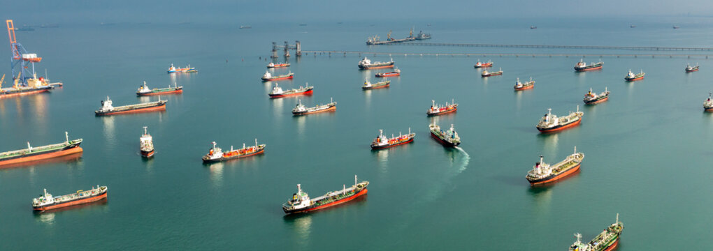 Aerial view of numerous oil and gas tankers anchored in a bay, showcasing large-scale maritime energy transport and dense commercial sea traffic.