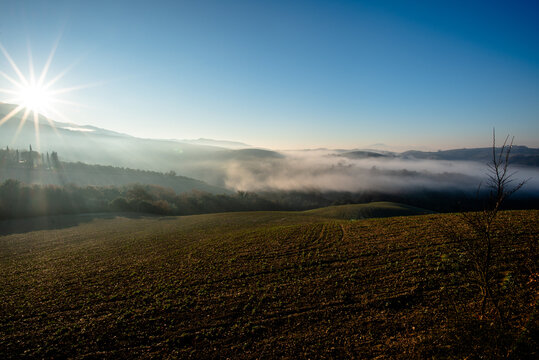 Sunrise over misty hills and cultivated fields in Italy