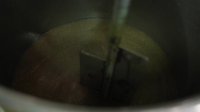 Mixing Process in the Factory: A close-up view capturing the dynamic action of industrial mixing, where the swirling motion of the blades blends ingredients within a large container.