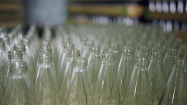 Bottles in Row: A close-up perspective of rows of glass bottles, highlighting the repetitive, transparent forms, potentially in an industrial or production context.