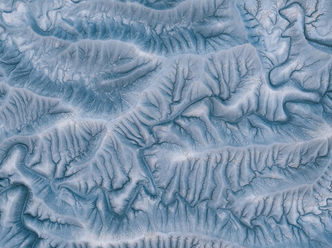 Aerial view of intricate eroded badlands and mudstone formations around Factory Butte showing deep ridges, gullies, and a dendritic drainage pattern in Wayne County, Utah, United States.